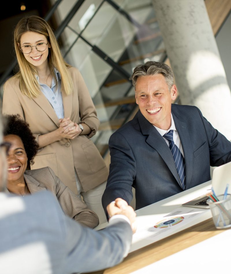 Business people shaking hands while sitting by the desk in the office